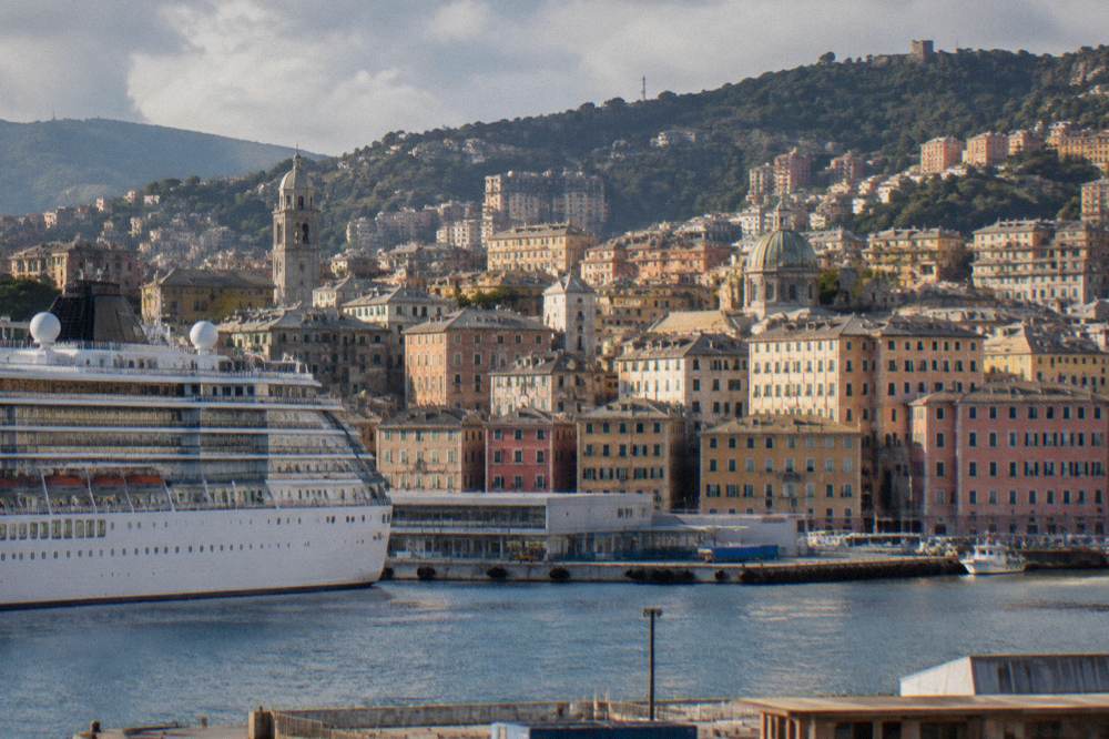 Cruise ship moored at a Genoa passenger terminal with the city rising behind the docks