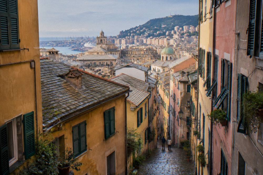 Narrow cobbled lane in the old town of Genoa between tall shuttered buildings