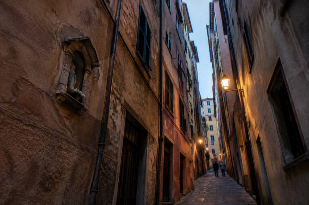 Narrow caruggi lane in Genoa old town between tall coloured buildings