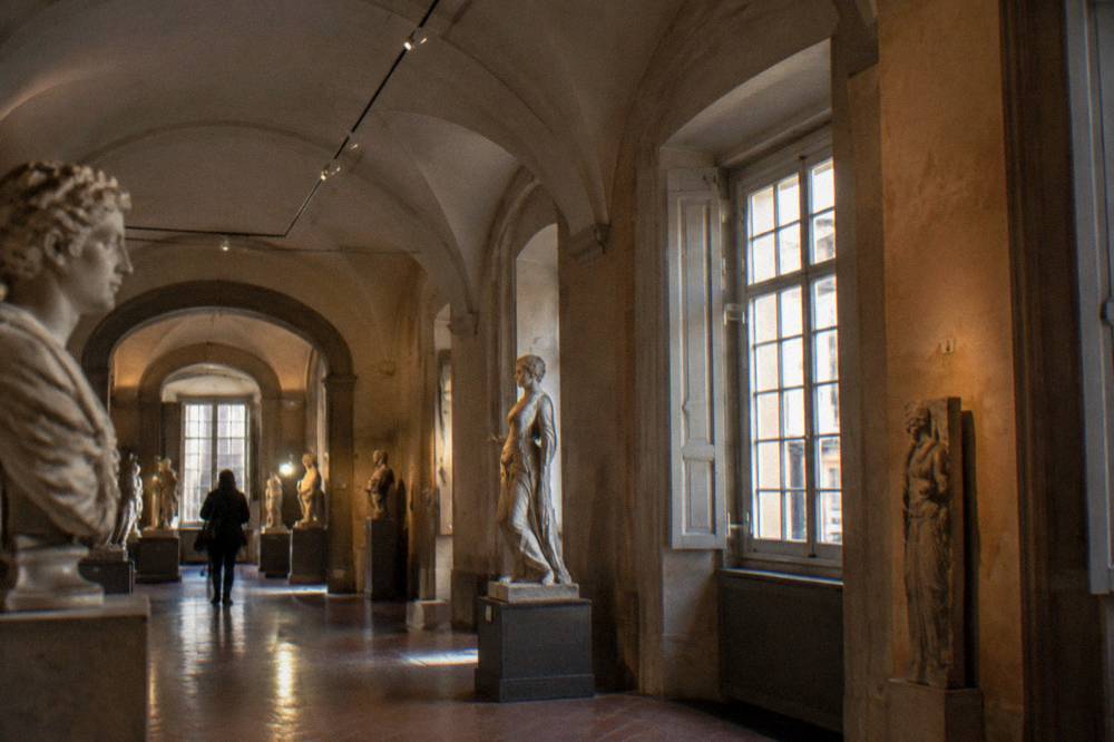Museum gallery with sculptures displayed under vaulted ceilings