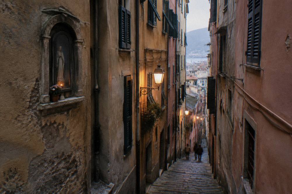 Narrow caruggi alley in Genoa old town lit by warm lamps at dusk