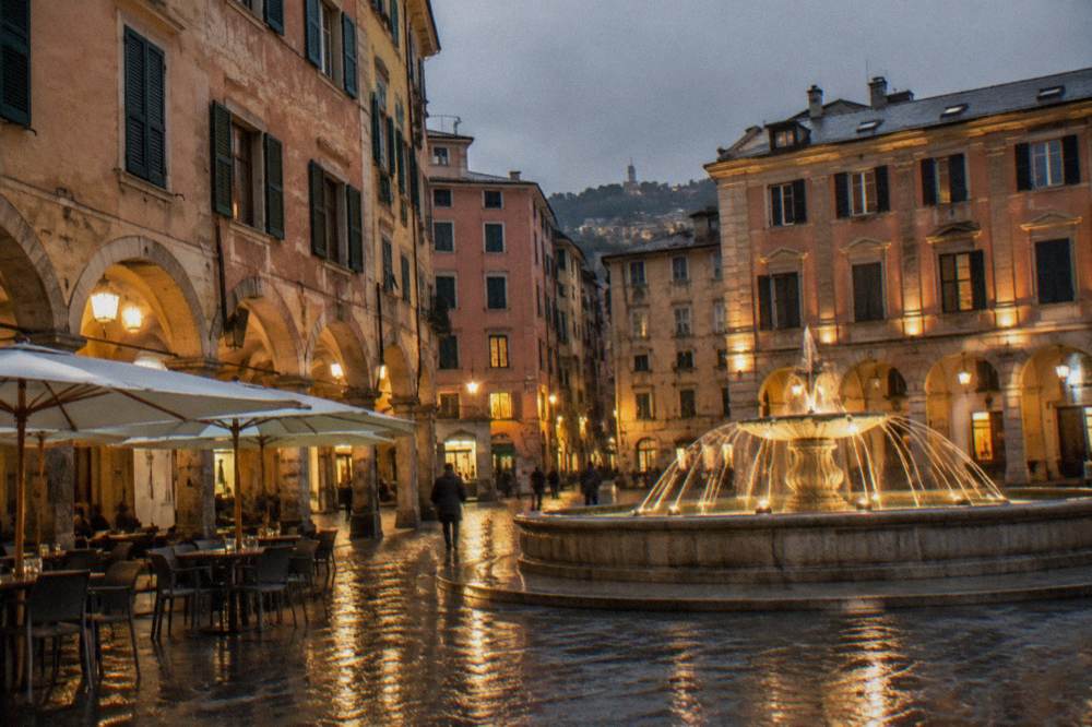 Floodlit fountain and illuminated buildings around a central city square at night