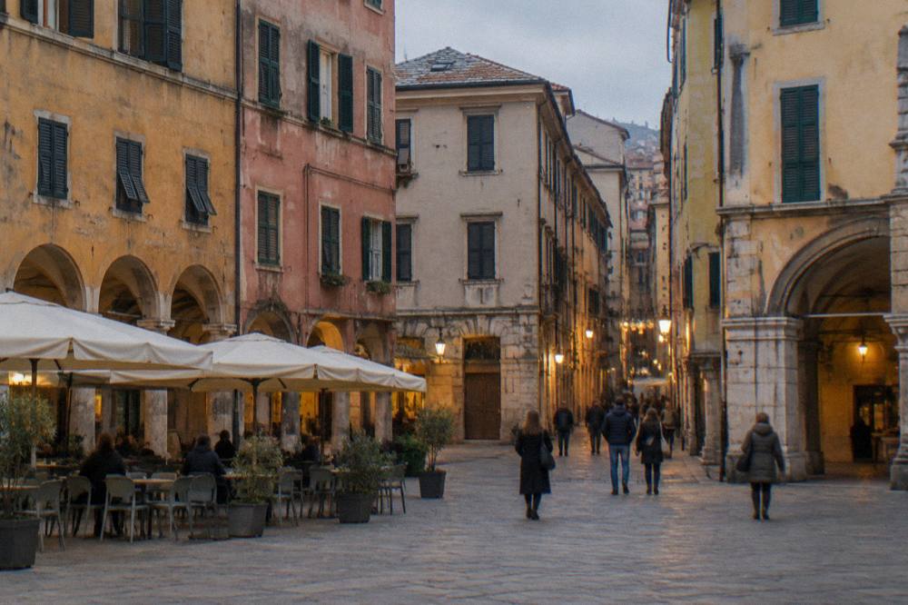 People walking through a narrow lit medieval street in the evening
