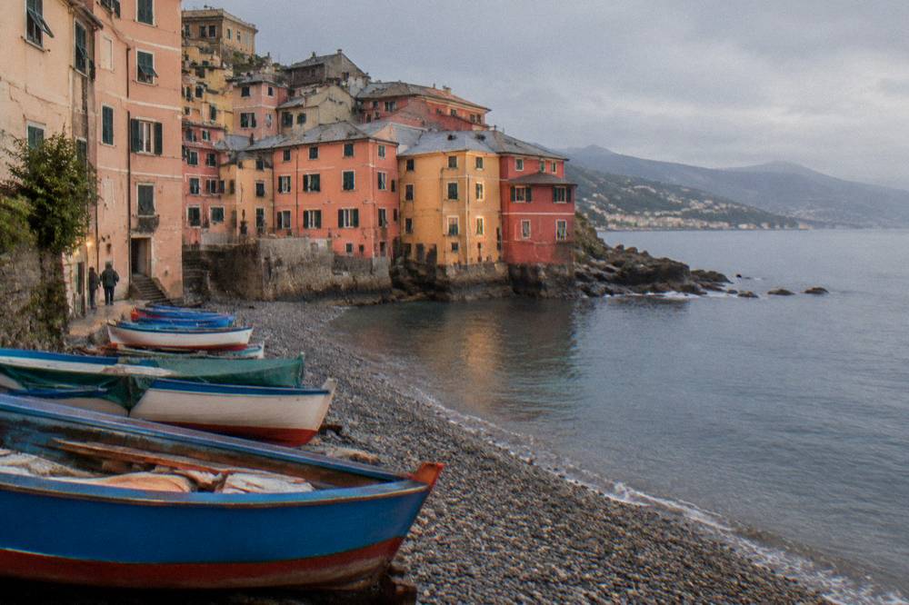 Colourful fishing boats and houses around a small pebble beach at Boccadasse