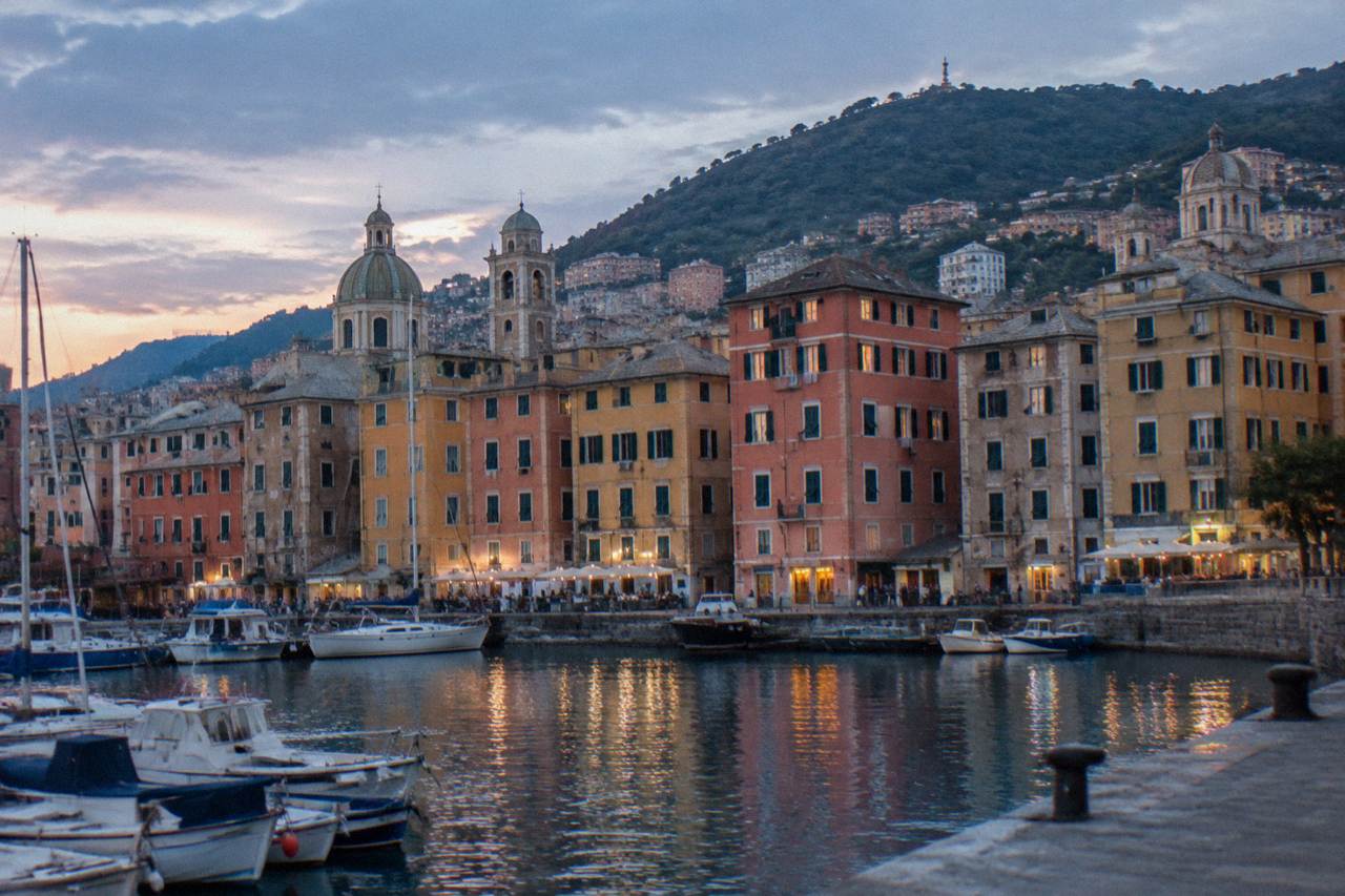 Colourful Ligurian waterfront buildings rising above a small harbour at sunset