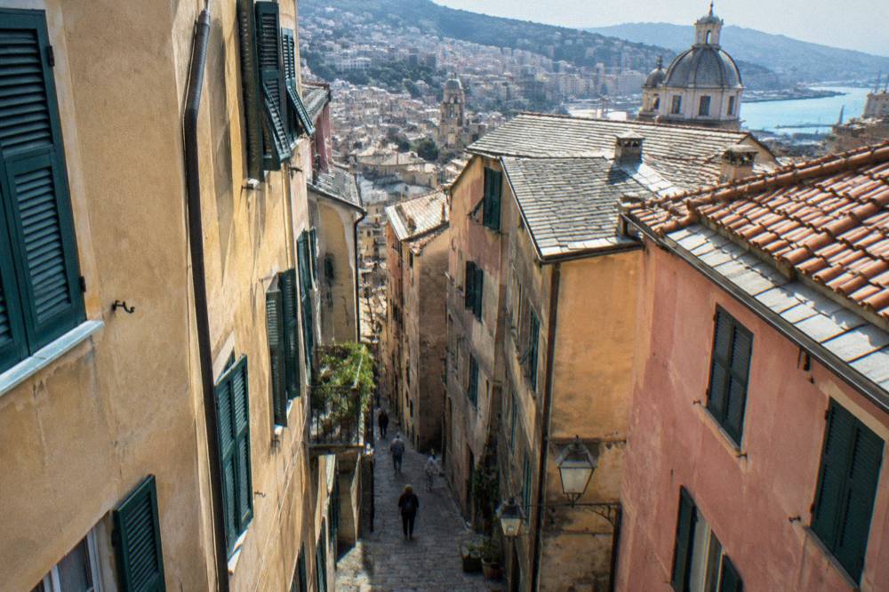 A narrow medieval lane in Genoa between tall stone buildings