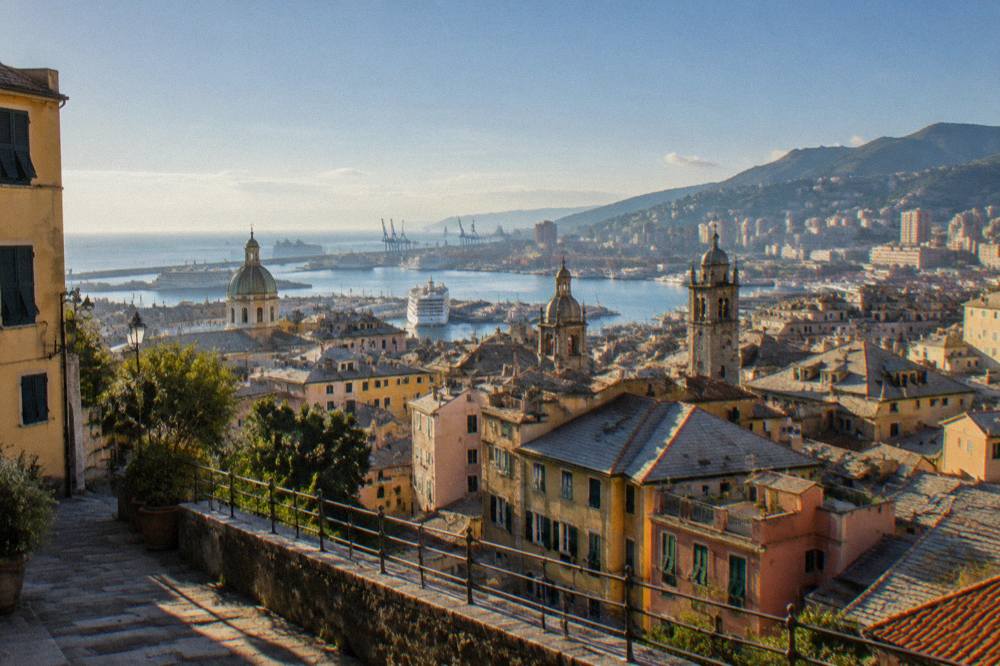 Panoramic view over a Ligurian city rooftops and harbour from a hillside terrace