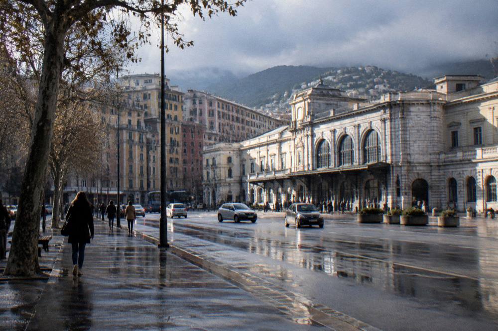 Wet reflective street in an old city with rain clouds over the hills