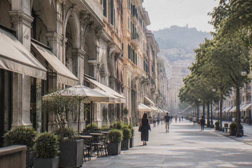 A wide tree-lined avenue with porticoed buildings and shop awnings on both sides