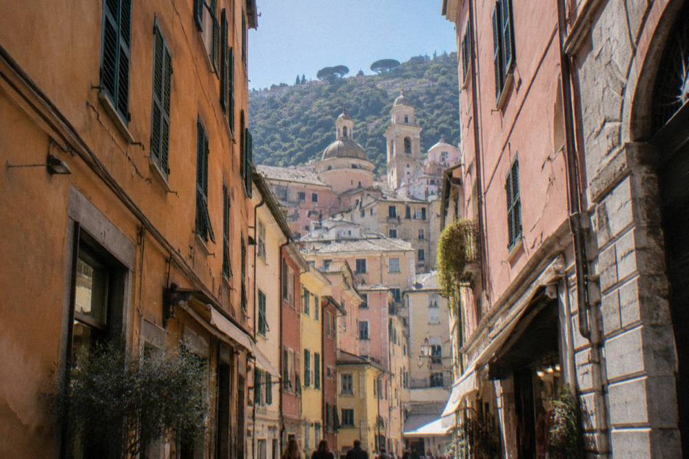 A narrow old town lane with small shopfronts, hanging signs and stone walls
