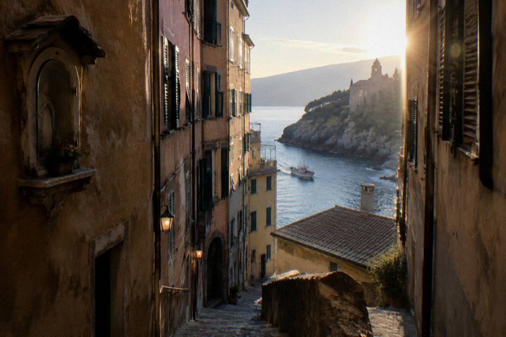 A small boat approaching a rocky cove with an abbey on the Ligurian coast