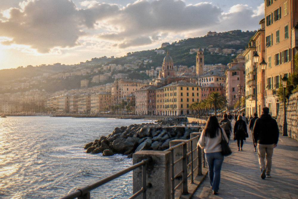 A seaside promenade in Genoa at golden hour with people walking