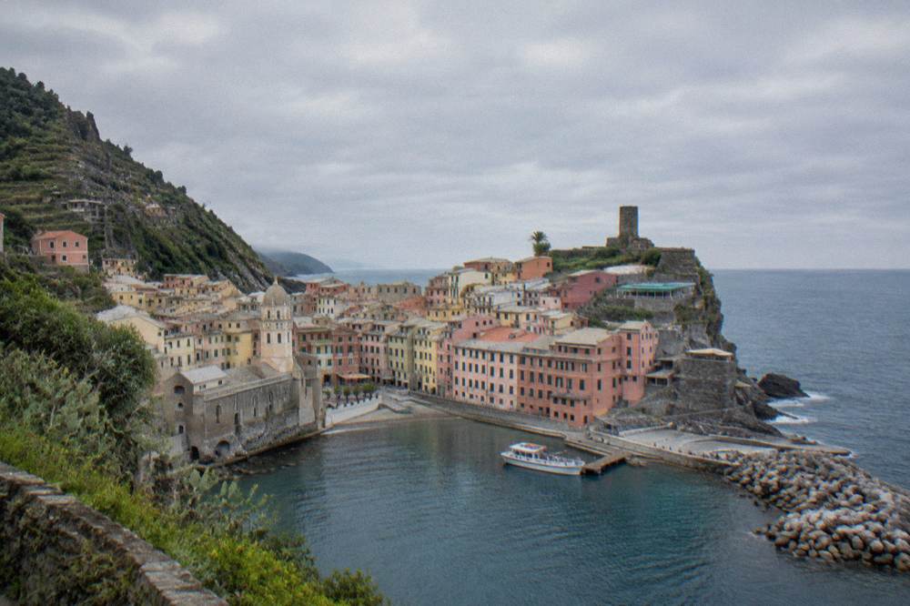 A small passenger boat moored at a wooden jetty below pastel houses