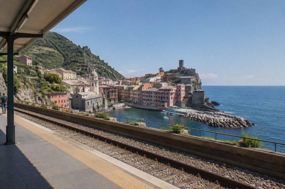 A station platform in the morning with a seaside town visible beyond the tracks