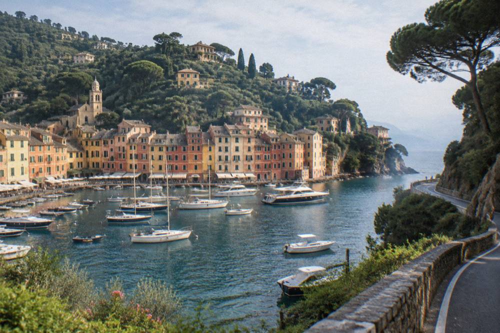 A narrow coastal road winding along a wooded cliff above the sea