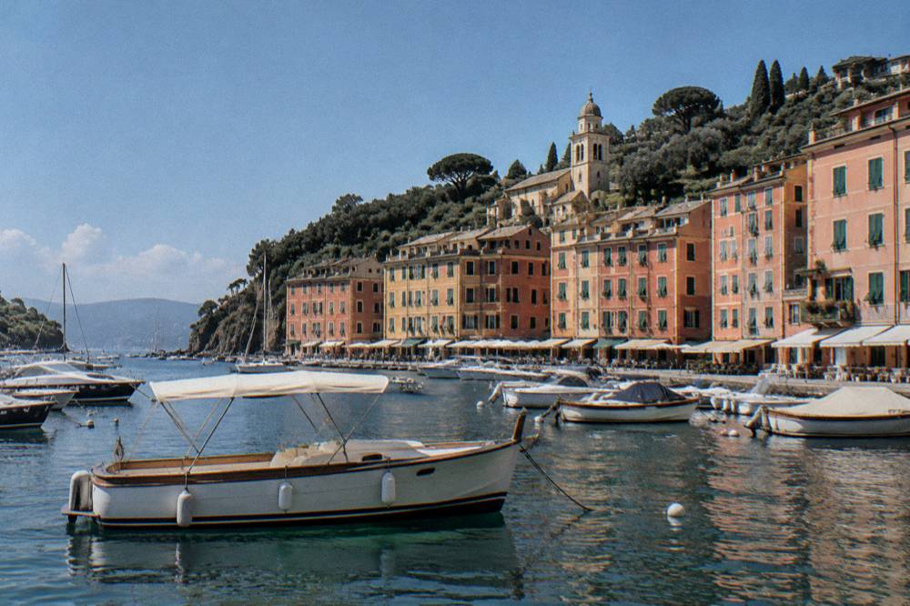 A private boat moored in a small harbour surrounded by pastel buildings