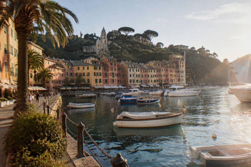 A seaside promenade with palm trees and pastel buildings along a curved bay