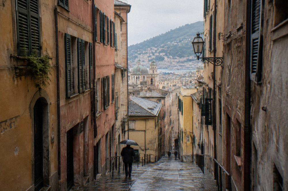 Narrow medieval alley in the old town of Genoa with tall stone buildings on both sides