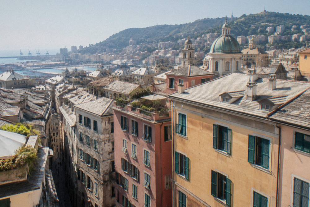 Sunlit rooftops of Genoa with the hills rising behind the city