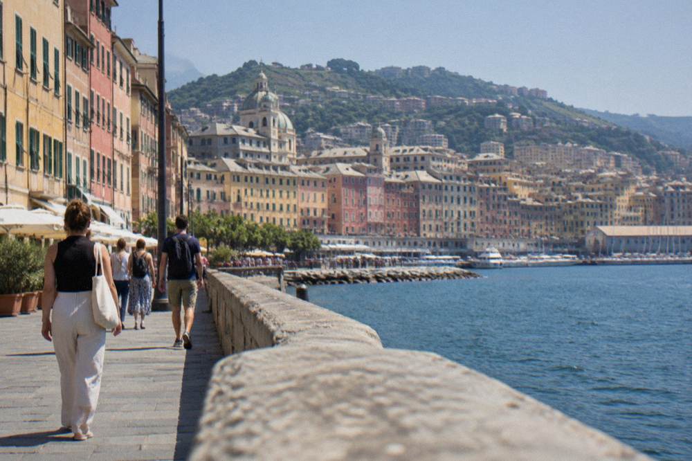People walking along a sunny promenade in Genoa near the sea