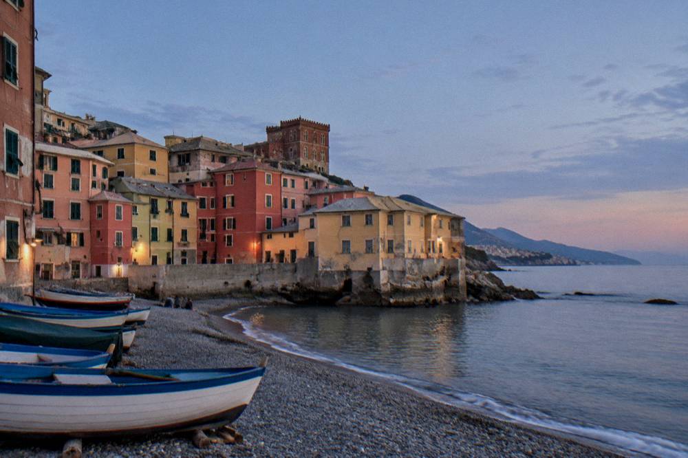 A small pebble beach with colourful buildings and fishing boats at Boccadasse