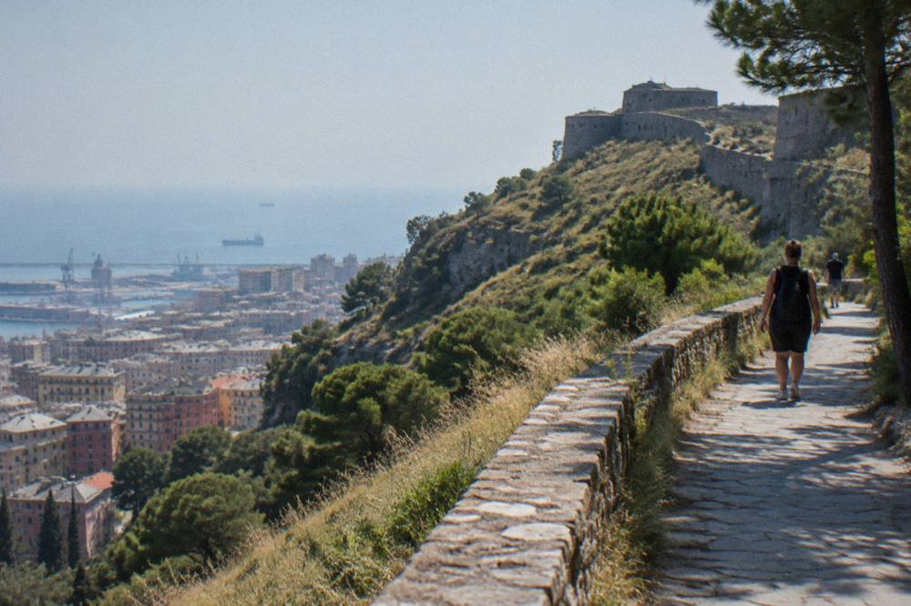 A paved ridge path with sea views behind a city rooftline