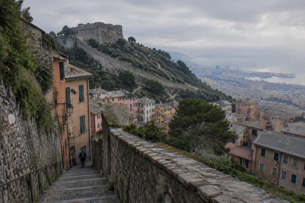 A steep stone lane with high walls and steps climbing through a Ligurian district