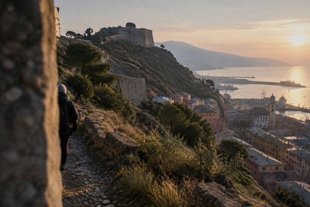 Sunset light on a coastal path with a village and harbour below