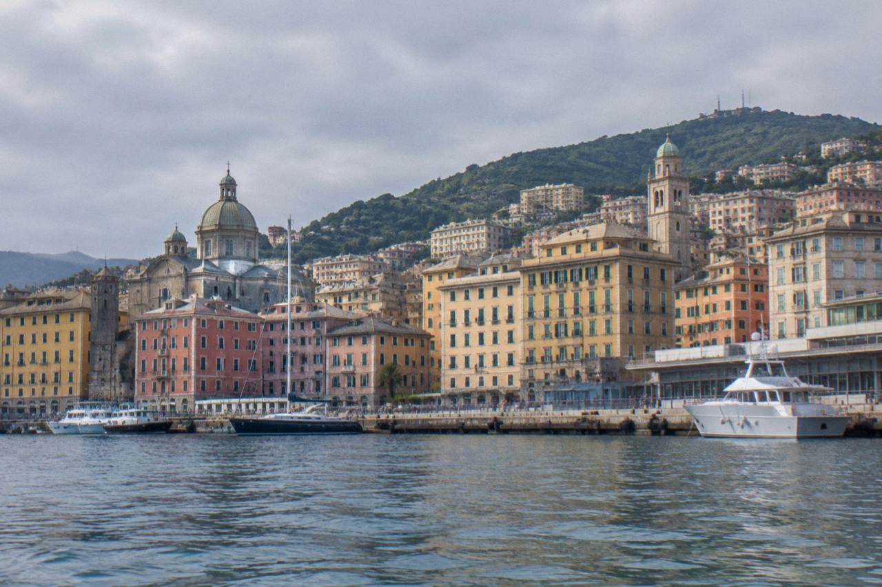The harbour of Genoa seen from the water with hills rising behind the city