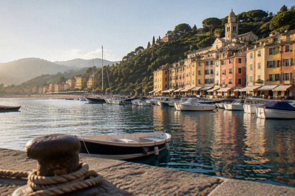 A sandy beach with pastel buildings and hills behind it on the western Ligurian coast