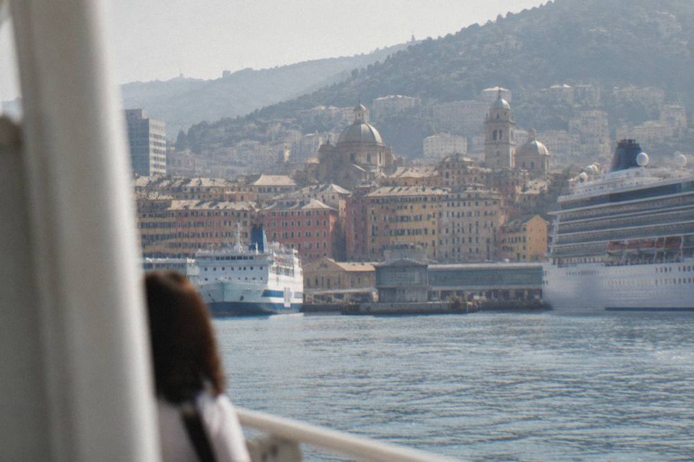 Ferry and cruise ships moored at Genoa port terminals seen from the water