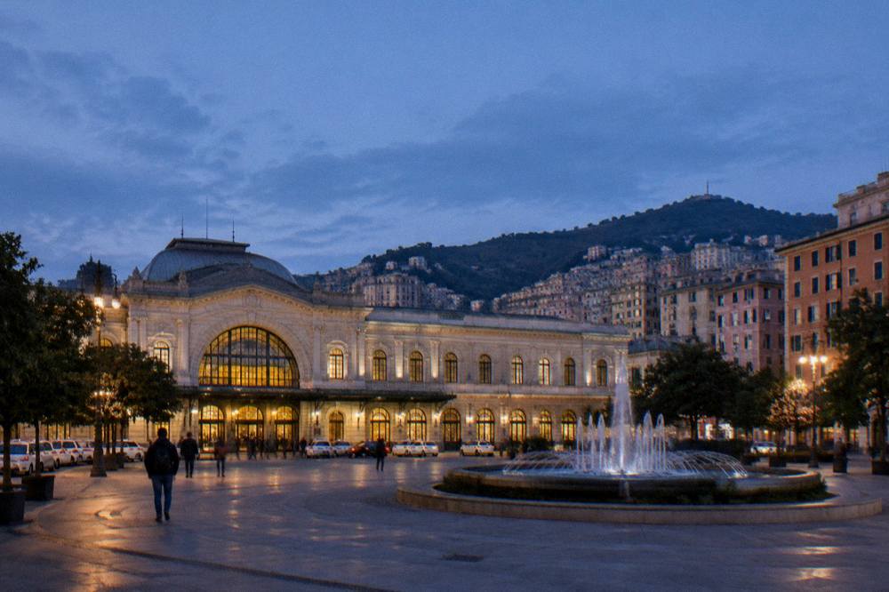 Evening view of an illuminated Italian square with a fountain and opera house facade