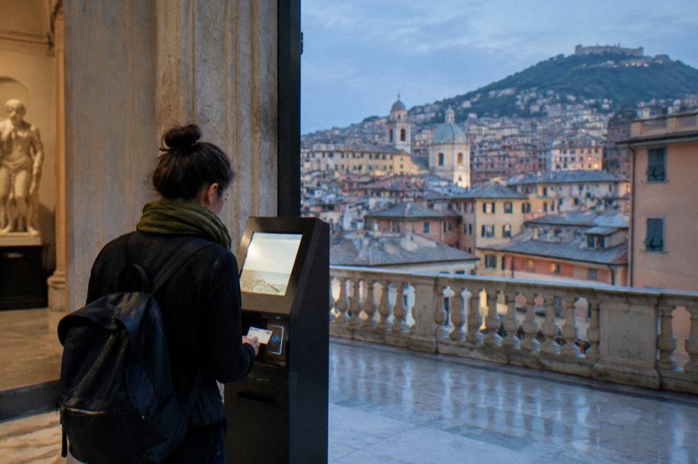 A traveller paying with a contactless card at a museum ticket machine in Genoa