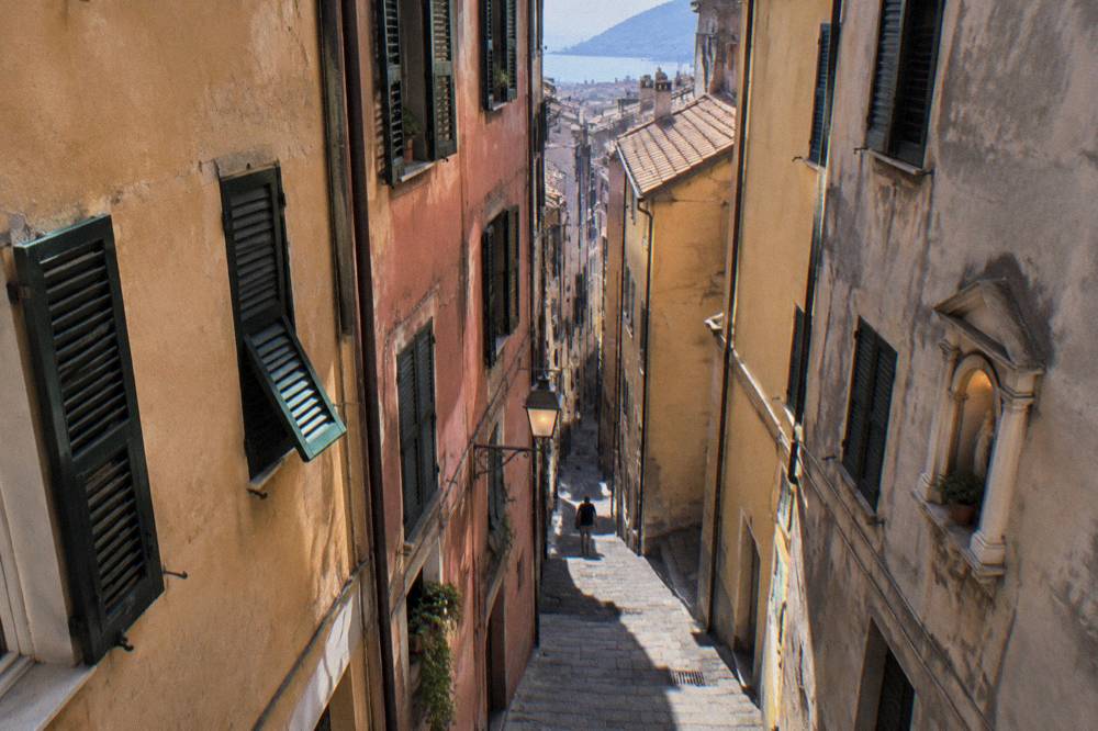 Narrow caruggi lane in Genoa's old town with tall shuttered buildings