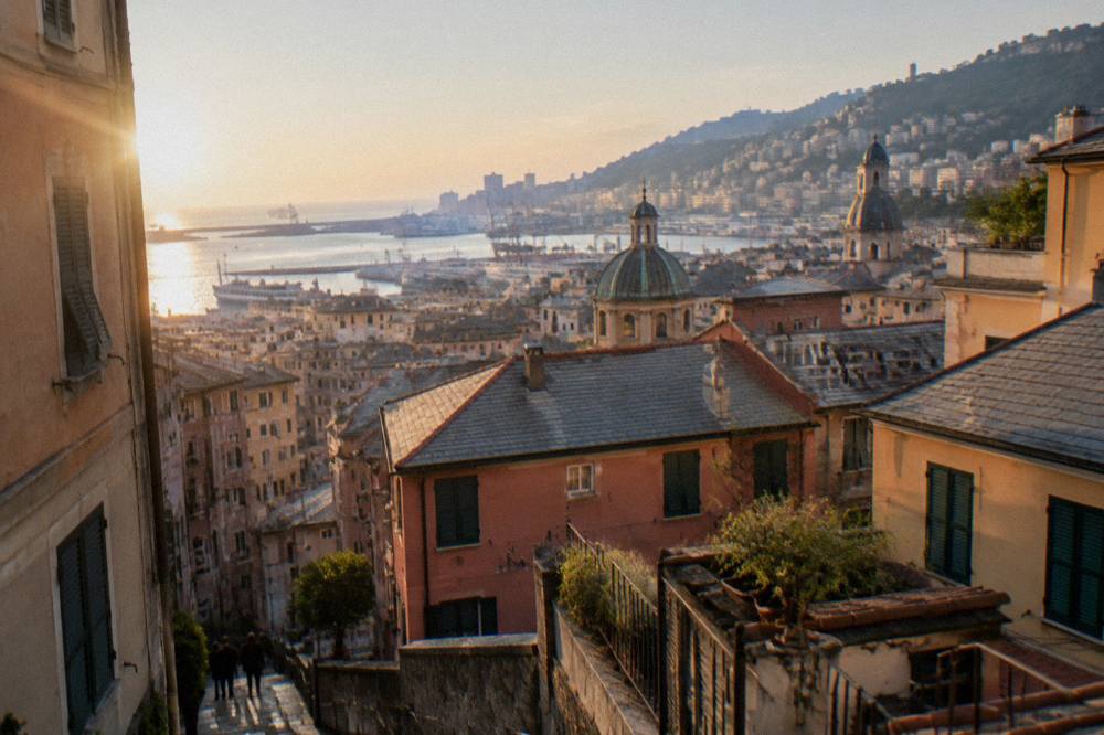 Sunlit rooftops of Genoa descending toward the harbour at golden hour