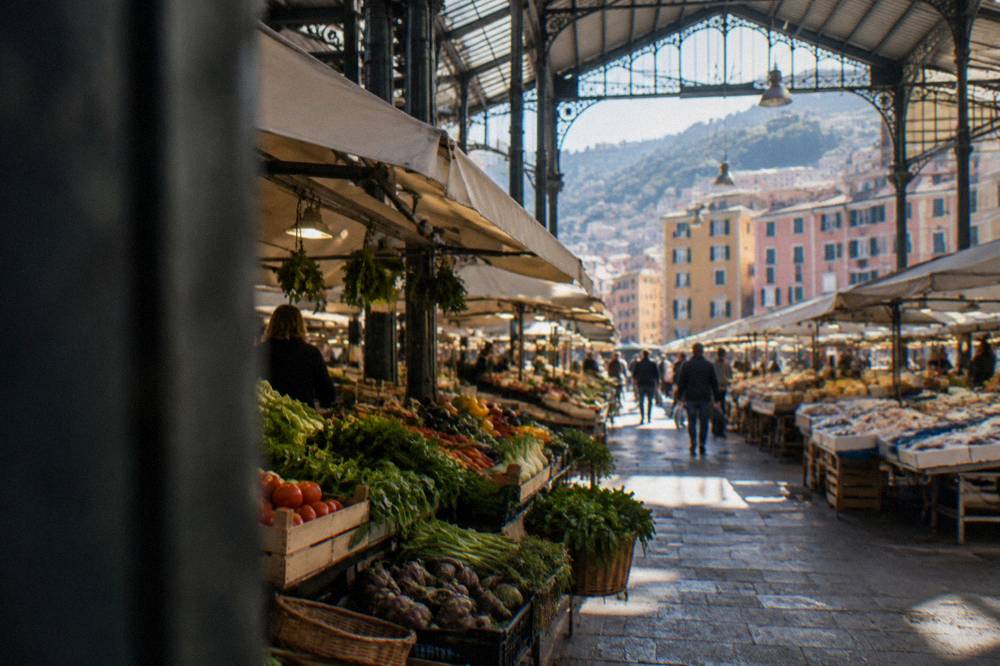 A market stall with stacked vegetables and baskets under an ornate iron roof
