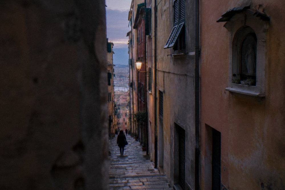 Narrow caruggi lane in the Genoa old town with tall coloured buildings