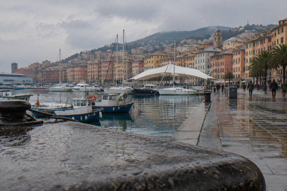 Fishing boats and pastel buildings along the old harbour at the Porto Antico in Genoa