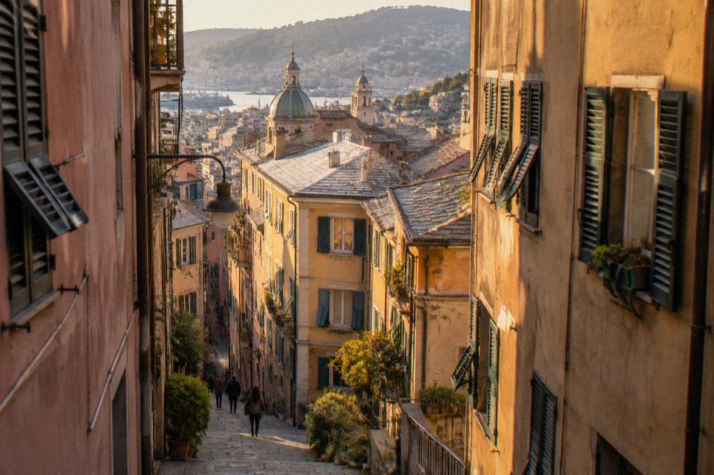 Narrow alley in the medieval old town of Genoa with tall shuttered buildings on both sides