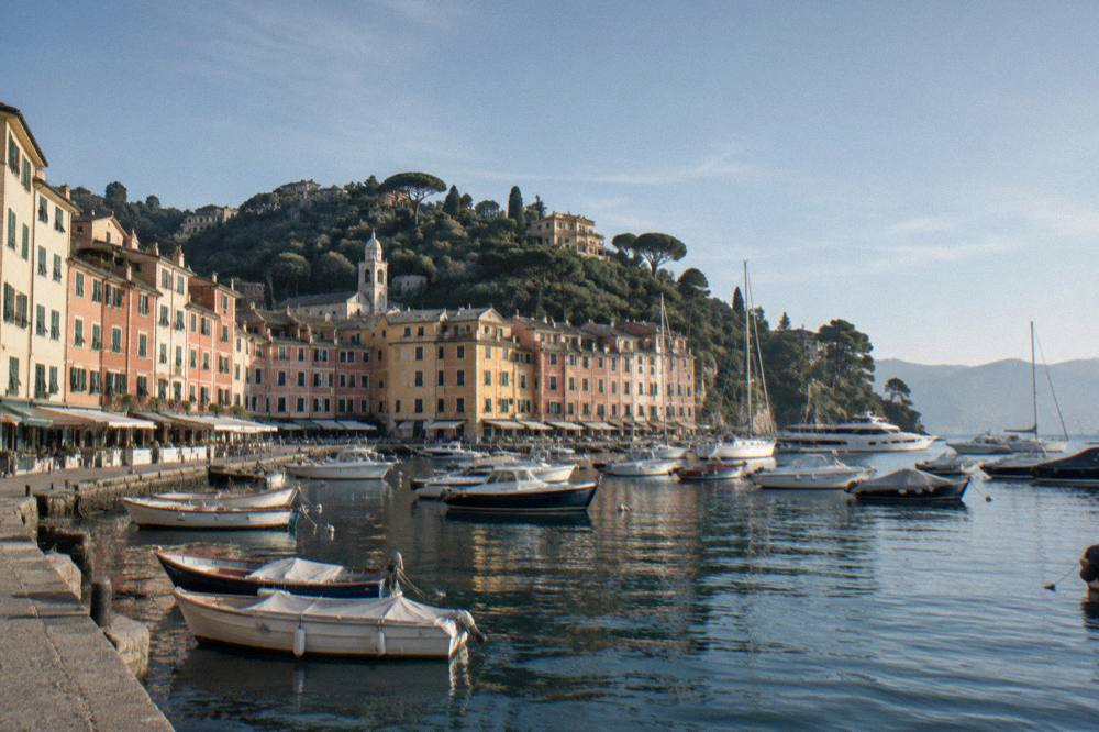 Pastel houses of Portofino around its small harbour with boats at anchor