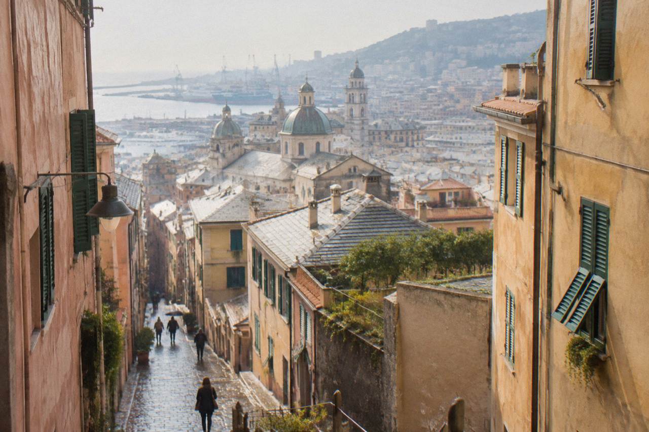 Wet cobblestone street in the old town of Genoa with narrow alley walls and reflections on the stones