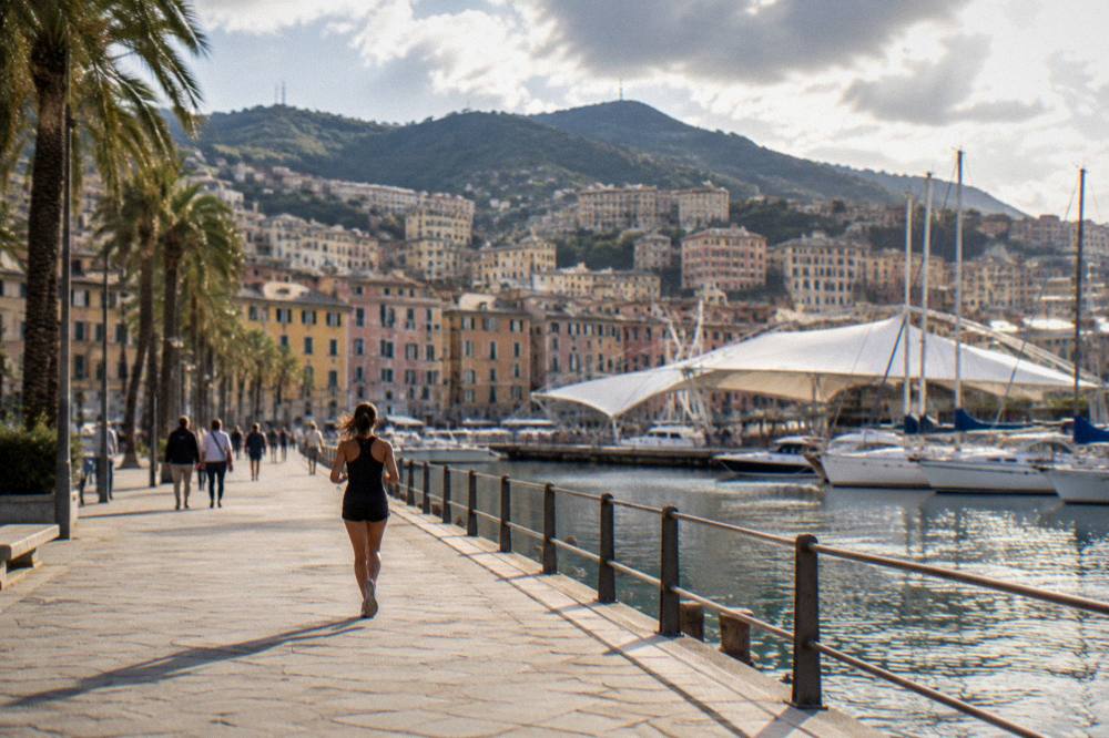 People walking a seaside promenade with palm trees under a warm sky