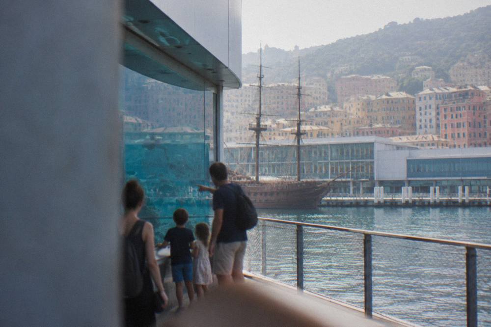Children looking at a large glass aquarium tank while parents point at fish