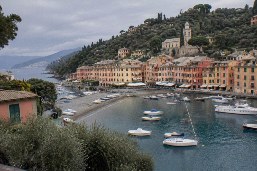 Colourful houses of a small fishing village wrapped around a pebble beach with small boats