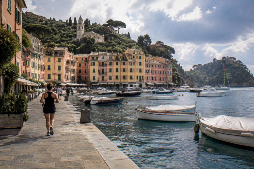 Rocky headland with a small harbour village and wooded slopes above blue Mediterranean water