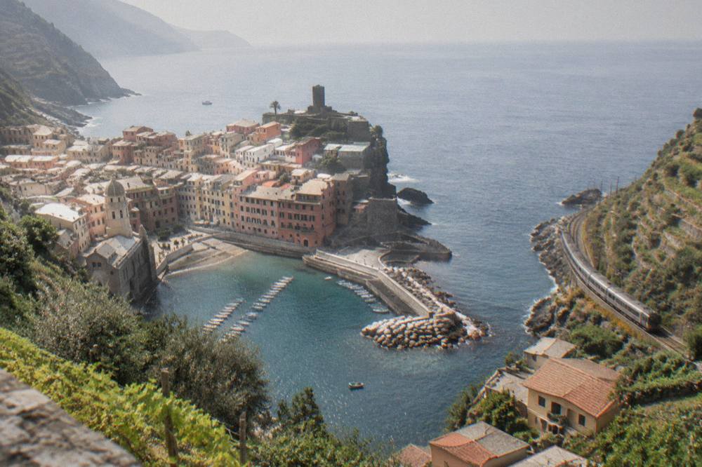 A coastal train passing between terraced hills and the sea on the Ligurian riviera