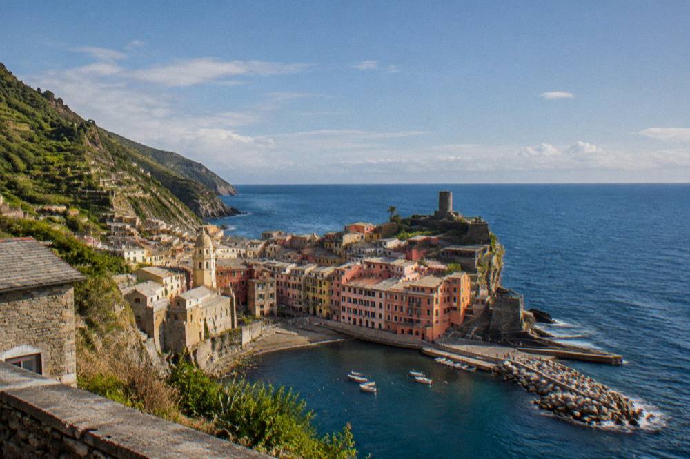 A stone watchtower above a village rooftop and the open sea