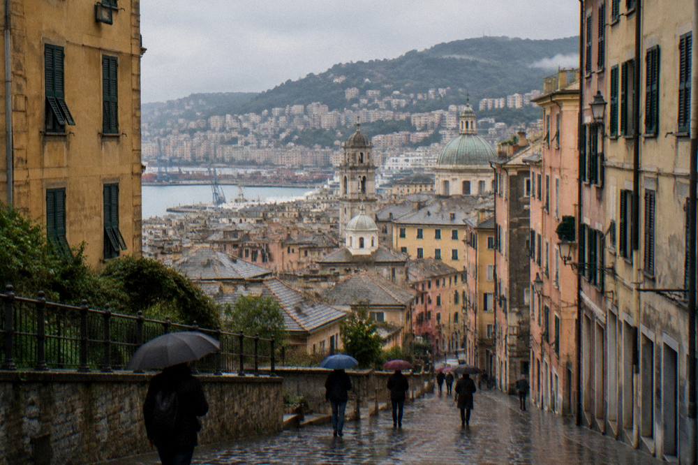 Rain-slicked cobblestones in a Genoa street with people under umbrellas