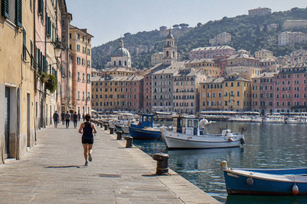 Fishing boats and coloured apartment buildings along a Genoa waterfront quay