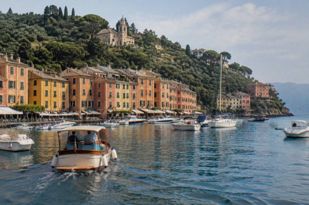 A boat approaching the harbour of Portofino with coloured houses along the shore